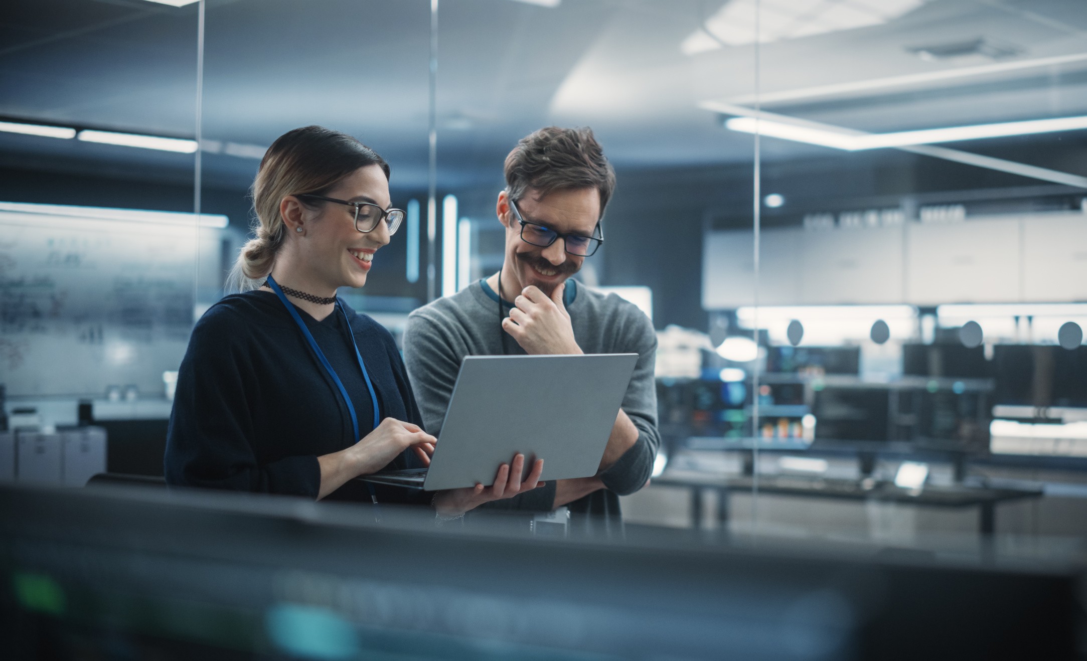 Mann und Frauen schauen lachend auf einen Laptop